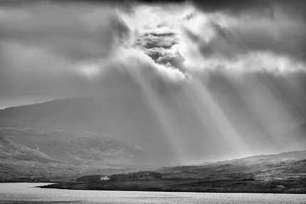 A break in the clouds reveals the sunlight and beams radiate down upon the landscape.