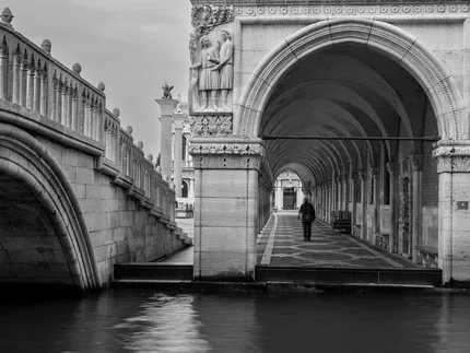 A man walking away under the arches of Doge's Palace Venice.