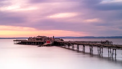 Birnbeck Pier at sunset with pink and purple skies.