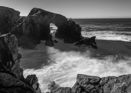 Black and white version of Star a'Phris in Lewis.  White waves swirl around the rich with its natural archway.