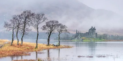 Ruined stone castle on an island in Loch Awe, backed by misty mountains