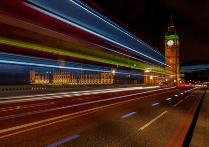 A London bus passes over Westminster bridge passing Big Ben using slow shutter speed