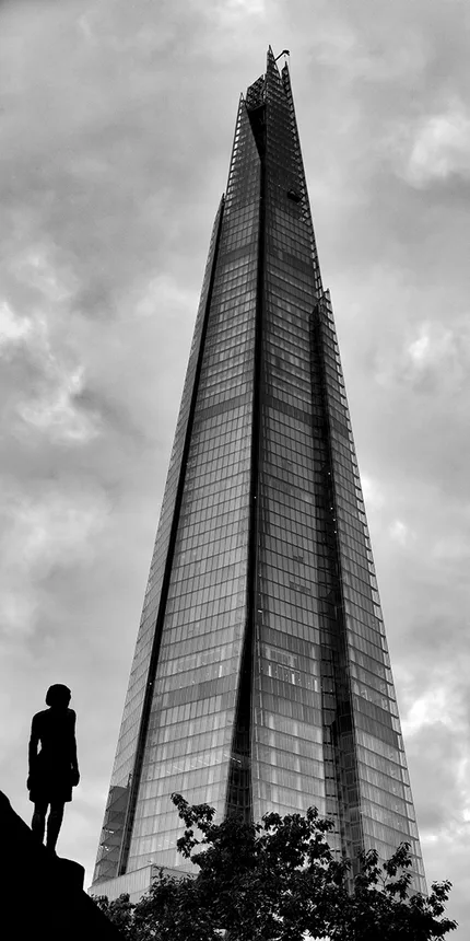 A small statue of a little girl looks towards the Shard in London