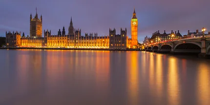 Westminster Bridge and Houses of Parliament and Big Ben light up by beautiful night lights with reflections in the Thames. .