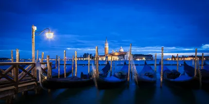 gondolas bob up and down in front of St Mark's square during the morning blue hour.