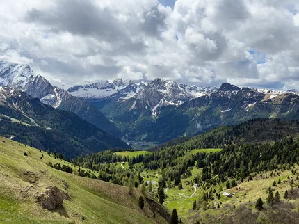 A green valley stretches towards the peaks of the Dolomites.
