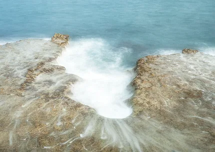 A slow exposure of the tide filling a basin in the rock at Portland, Dorset.  Soft water filters onto the rock.